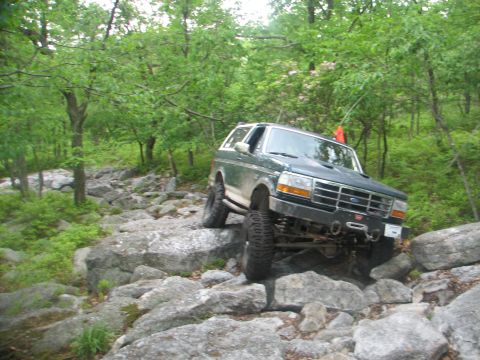 1992 Ford Bronco - This Ford Bronco navigates a challenging rocky terrain on a wooded trail, its off-road capabilities.