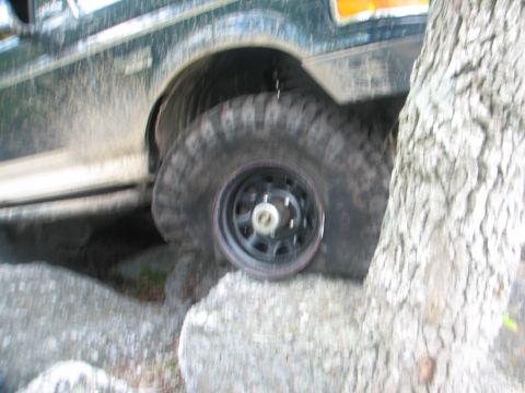 1992 Ford Bronco - A 1992 Ford Bronco navigates rocky terrain, its large tire clearly visible.