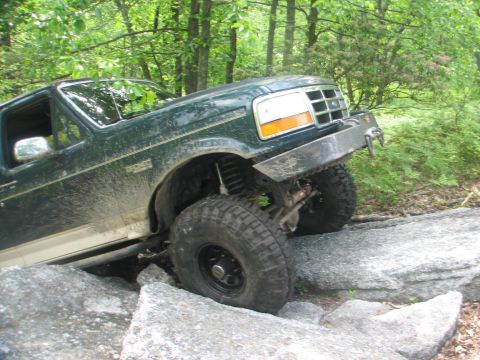 1992 Ford Bronco - This modified Ford Bronco navigates a rocky obstacle on a wooded trail.