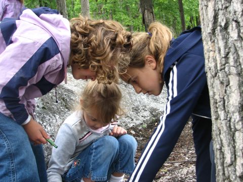 1992 Ford Bronco - Children gather in a wooded area, intently observing something on the forest floor.