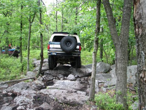 1992 Ford Bronco - This Ford Bronco is tackling a challenging off-road course with large rocks and mud.