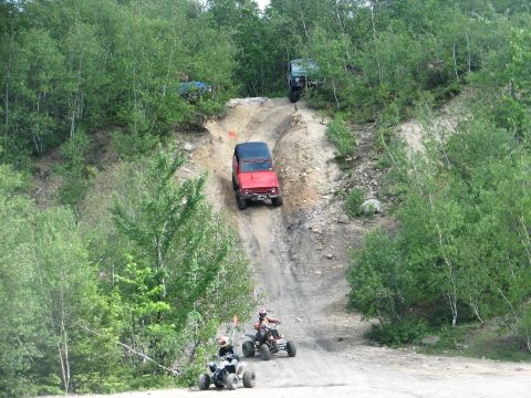 1992 Ford Bronco - Multiple off-road vehicles navigate a steep, wooded incline.