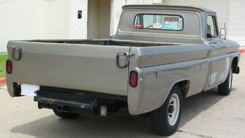 Gray pickup truck rear view, showing tailgate, taillights, and tow hitch