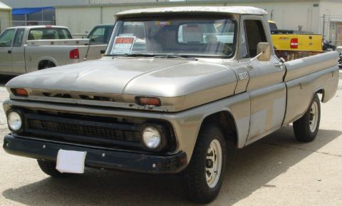 1986 Ford Bronco - This vintage pickup truck is parked outdoors with other vehicles in the background.