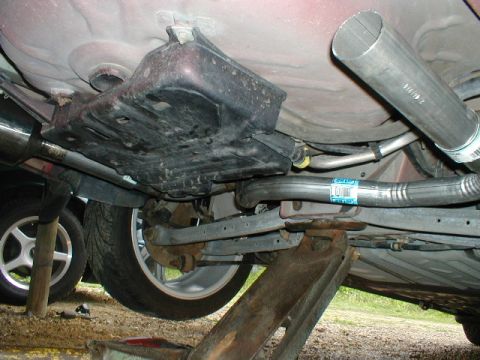 1998 Ford Taurus - The underside of a vehicle is shown, with focus on the exhaust system and suspension components, supported by jack stands.