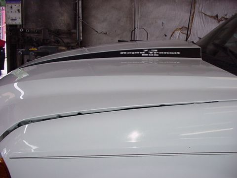 2000 Ford Excursion - The hood of a white SUV displays "7.3L Power Stroke" and "Rapid Transit Bus" text on a black stripe.