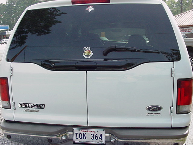 Rear view of a white 2000 Ford Excursion Limited with a Louisiana IQK 364 license plate and various stickers