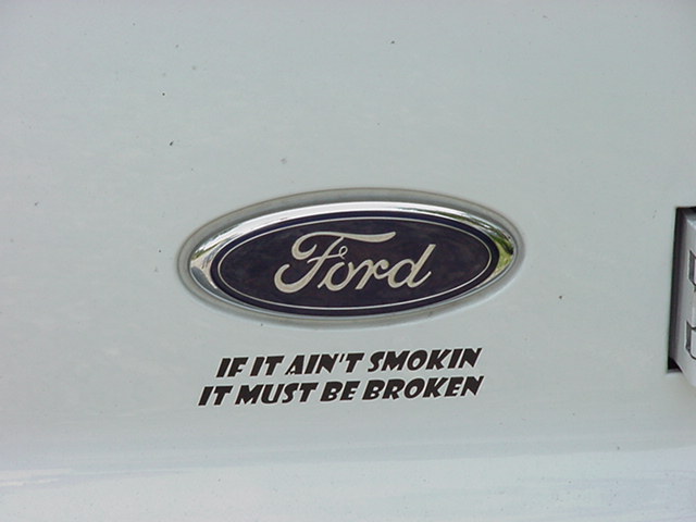 White vehicle panel with a Ford oval emblem and a sticker reading 'IF IT AIN'T SMOKIN IT MUST BE BROKEN'