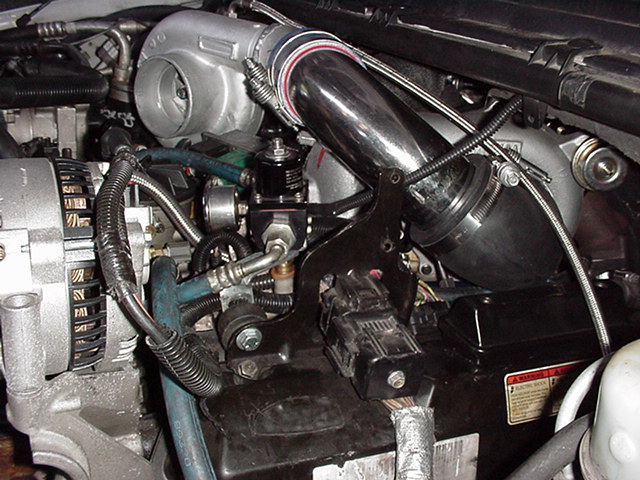 Engine compartment with a silver turbocharger, chrome piping, and an alternator