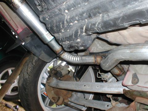 1998 Ford Taurus - A close-up view of a vehicle's undercarriage reveals the exhaust system and rear suspension components.