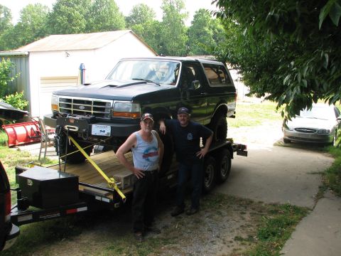 1992 Ford Bronco - Two men pose with a black Ford Bronco loaded onto a trailer, ready for transport.