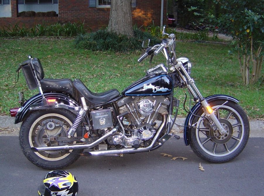Side view of a dark blue Harley-Davidson motorcycle parked on a street, with a helmet on the ground