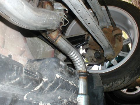 1998 Ford Taurus - Close-up of the exhaust pipe and rear suspension components of a vehicle.