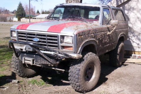 1996 Ford Bronco - This lifted Ford Bronco is caked in mud, suggesting recent off-road use.
