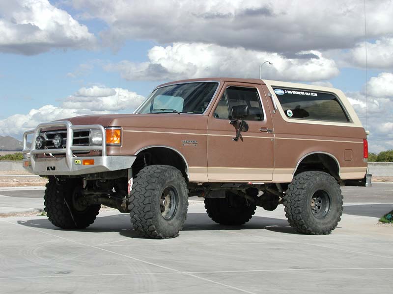 Tan lifted 1989 Ford Bronco on large mud tires outdoors