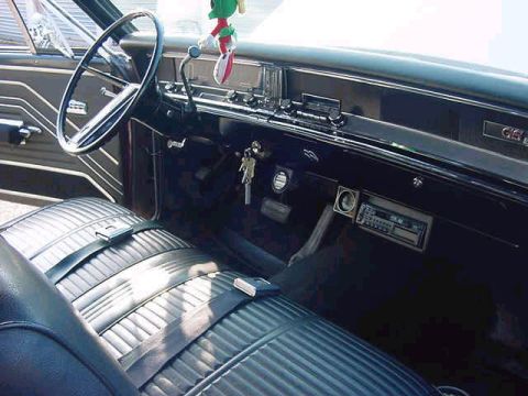 1986 Ford Bronco - The interior of a classic car features a bench seat, steering wheel, and dashboard with a radio.