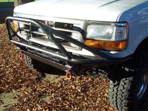 1996 Ford Bronco - Close-up of the front bumper and grille of a white Ford truck, an aftermarket brush guard and tow hooks.
