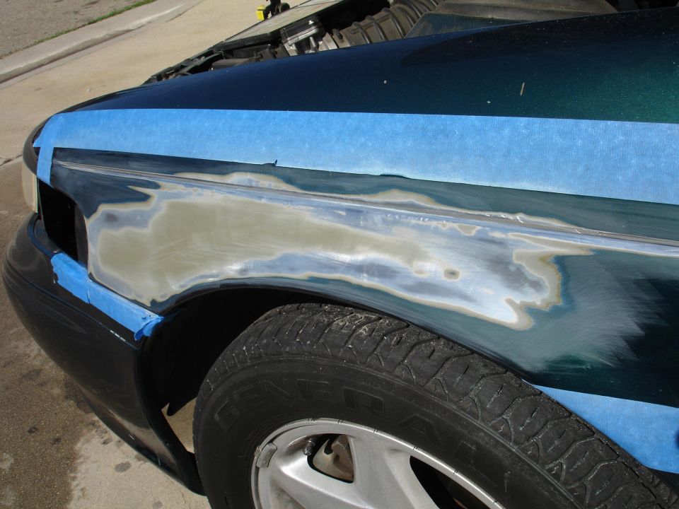 car fender with blue tape around sanded area, ready for body filler