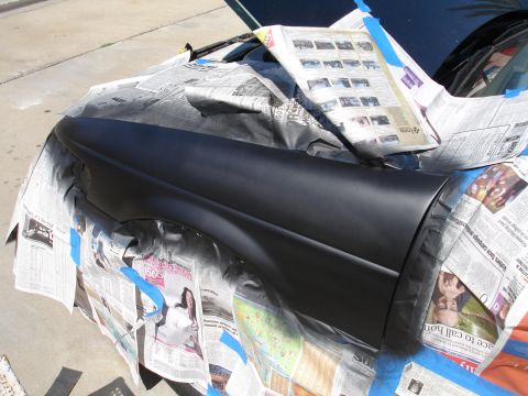 1995 Ford Taurus - A car fender is being prepped for painting with newspaper and masking tape.