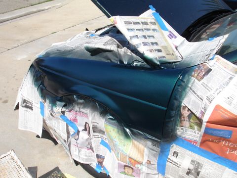 1995 Ford Taurus - A car fender is covered in newspaper and blue tape, preparing for a paint job.