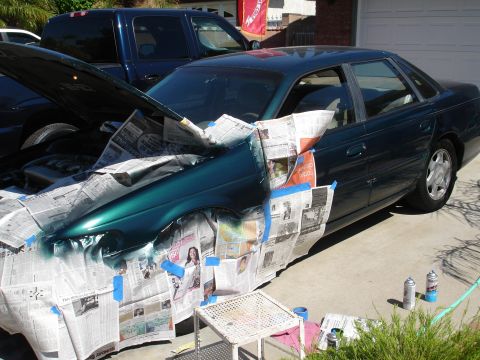 1995 Ford Taurus - A 1995 Ford Taurus is prepared for a paint job, with the fender and hood area covered in newspaper.