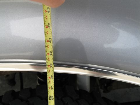 1995 Ford Bronco - A tape measure is held against the fender of a silver vehicle, indicating a measurement.