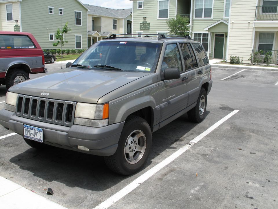 Gray Jeep Grand Cherokee parked in a lot, front quarter view