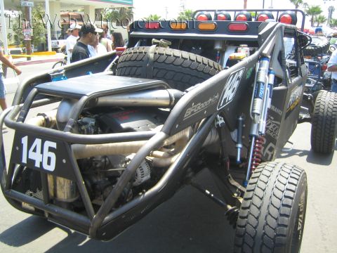 1990 Ford Bronco - Rear three-quarter view of a black number 146 tube-chassis off-road buggy showing its engine, spare tire and Fox shocks.