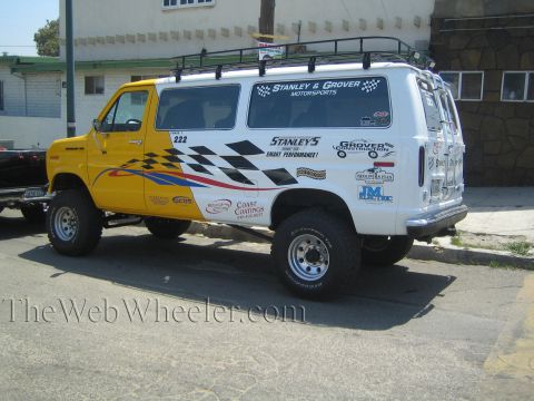 1990 Ford Bronco - lifted white and yellow Ford support van number 222 with checkered Stanley & Grover Motorsports graphics is parked on a street.