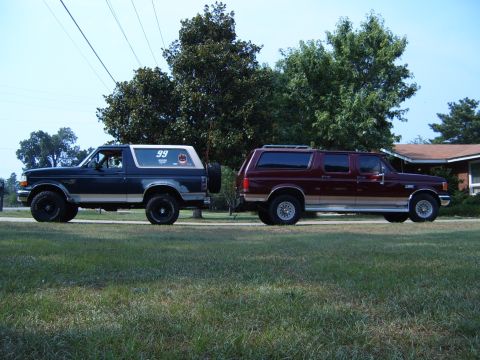1993 Ford Bronco - Two Ford SUVs, a Bronco and an Excursion, are parked on a lawn in front of a house.