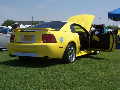2002 Ford Mustang - This yellow 2002 Ford Mustang is displayed with its hood and driver's door open at an outdoor event.