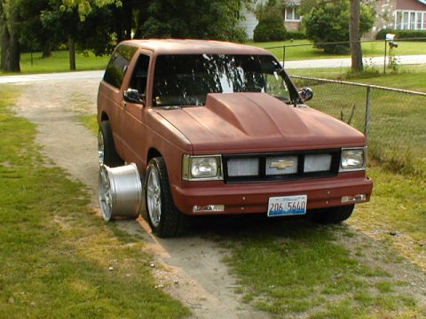 1998 Ford Taurus - This red SUV features a prominent hood scoop and a spare wheel placed beside it.