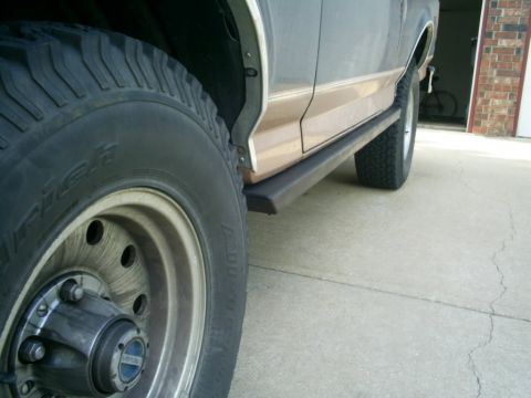 1994 Ford Bronco - Close-up view of the side slider and wheel of a two-tone SUV.