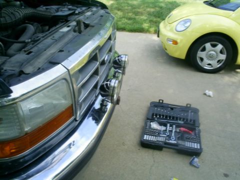1994 Ford Bronco - A truck's engine bay is exposed next to a yellow car, with a toolbox nearby.
