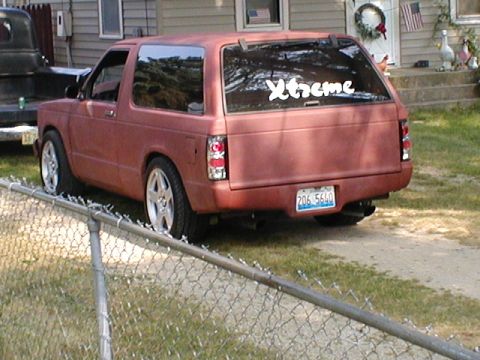1998 Ford Taurus - This red SUV is parked in front of a house, with a black truck visible to its left.