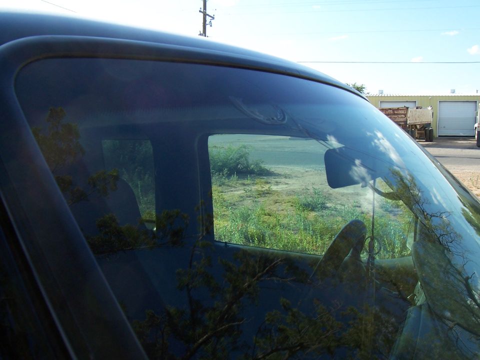 View from inside a vehicle, looking out the windshield and side window. Steering wheel and dashboard visible
