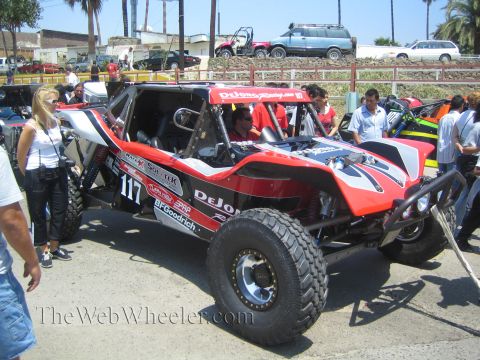 1990 Ford Bronco - Side view of a red, black and white tube-frame off-road race buggy number 117 with DeJong Racing and sponsor decals.