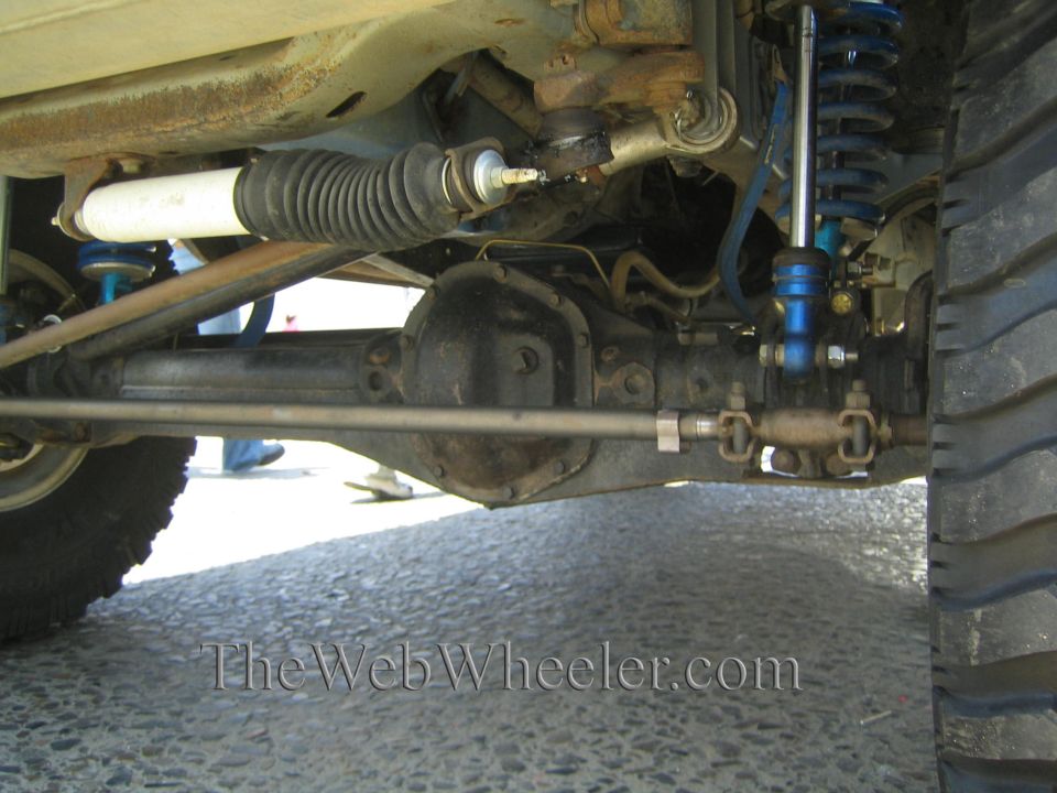 Underside of a lifted truck showing steering rack, blue coilover shock, and tie rods