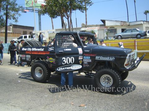 1990 Ford Bronco - Side view of a black vintage Ford desert race truck number 300 with River City Differential and Deaver sponsor graphics.