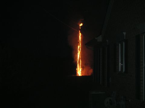 1994 Ford Bronco - A dramatic scene unfolds as fire erupts from a power line, illuminating the night sky near a brick structure.