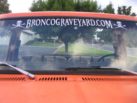 1979 Ford Bronco - View from inside an orange vehicle, looking through the windshield at a banner.
