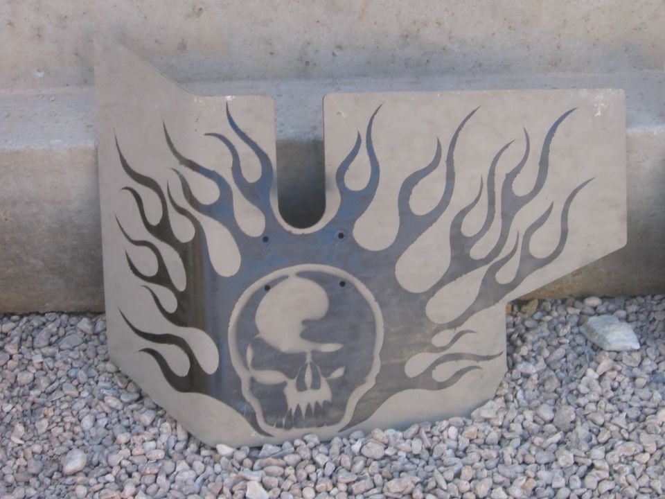 Metal plate with a skull graphic and flame decals. It's resting on gravel