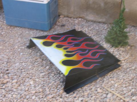 1979 Ford Bronco - A detached vehicle part with custom flame graphics lies on gravel.