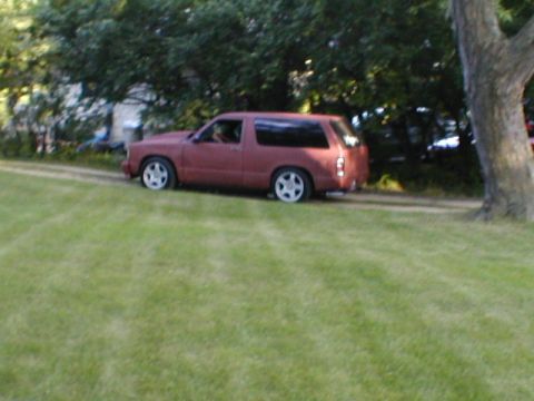 1998 Ford Taurus - A red two-door SUV is seen driving on a dirt road with a grassy area in the foreground.