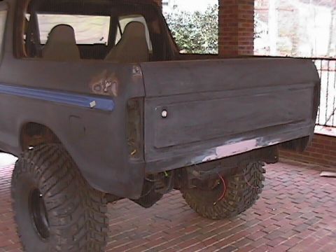 1979 Ford Bronco - Rear view of a dark SUV, possibly undergoing restoration, showing its quarter panel and tailgate.