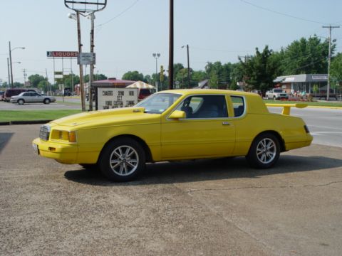 1986 Mercury Cougar - This modified 1986 Mercury Cougar LS features a prominent rear spoiler and a hood scoop, viewed from the front three-quarter angle.