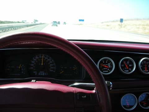1992 Ford Crown Victoria - View from the driver's seat shows a dashboard with a burgundy steering wheel, speedometer, and auxiliary gauges for boost, fuel, and water.