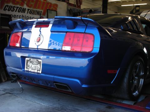 1992 Ford Crown Victoria - Rear view of a blue Ford Mustang with racing stripes, parked in a garage.