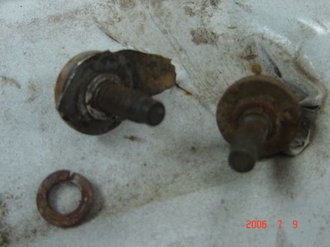 1993 Ford Bronco - Close-up view of rusted bolts and a split washer, indicating wear and tear on a vehicle part.