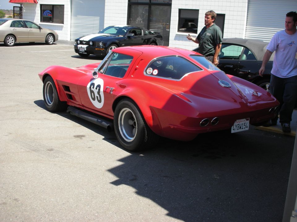 Red 1963 Corvette Stingray with racing number 63 on the door, parked outside